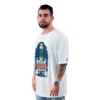 Un hombre está parado sobre un fondo blanco, vistiendo una camiseta gráfica blanca con el texto "The Blessing World Tour", que irradia vibraciones retro geniales que se hacen eco de los estilos clásicos de la cultura pop.