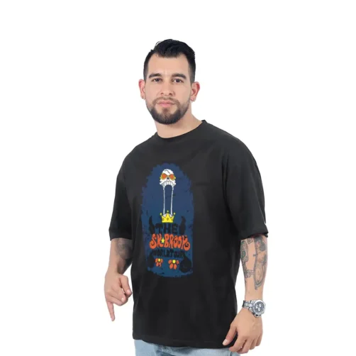Una persona que viste una camiseta negra con un diseño gráfico colorido que incluye texto e ilustraciones de la serie Estilos se encuentra sobre un fondo blanco.