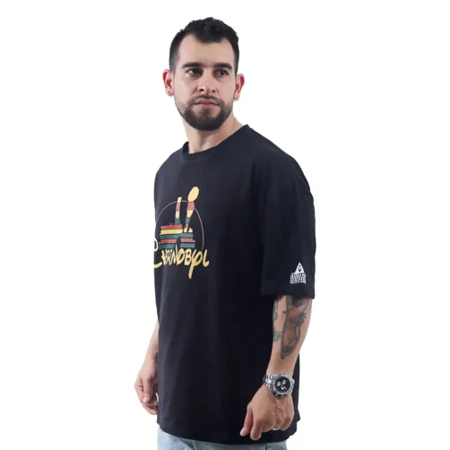 Un hombre barbudo con una camiseta Oversized de Chernobil / Disney, que fusiona estilos retro con vibraciones de la cultura pop, mira por encima del hombro y su reloj capta la luz.