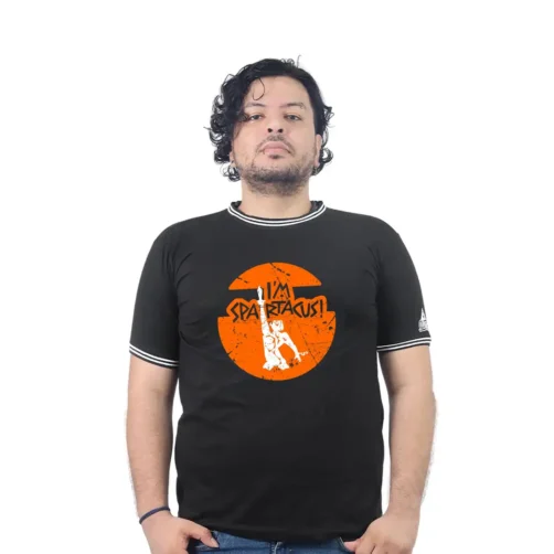 Una persona viste una camiseta negra con un diseño que grita "Soy Espartaco" sobre un fondo naranja, combinándose a la perfección con el estilo cultural pop.
