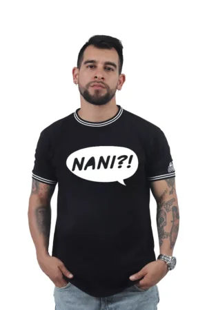 Un hombre con tatuajes luce una camiseta negra que muestra la frase "NANI?!" dentro de un globo de diálogo, encarnando la esencia de los estilos culturales pop.