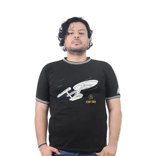 Una persona que viste el USS Enterprise (NCC-1701) - Camiseta Cuello Tejido, con un diseño de nave espacial, posa sobre un fondo blanco puro, encarnando la esencia de la cultura pop.