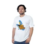 Una persona que viste una camiseta blanca con un gráfico de "Johnny Bravo", que muestra estilos retro, está parada sobre un fondo blanco liso.