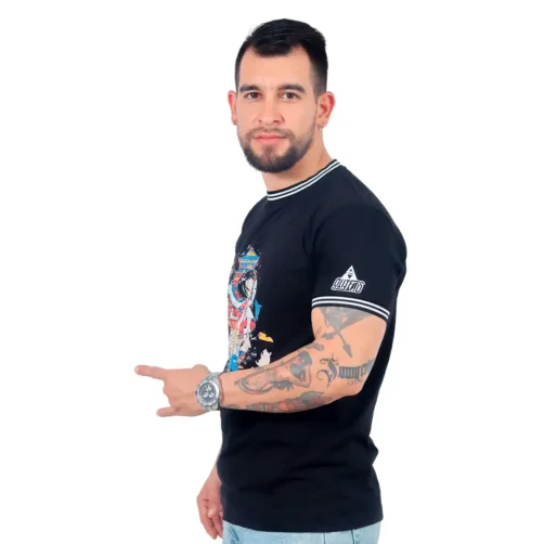 Un hombre con tatuajes, que viste una camiseta negra personalizada y un reloj, se encuentra sobre un fondo blanco y hace un gesto con la mano inspirado en los estilos de anime.