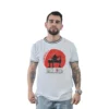 Hombre que lleva una camiseta gráfica blanca con un diseño rojo, que muestra a una persona sentada en una silla, y jeans azul claro, que incorporan estilos culturales pop sobre un fondo blanco liso.