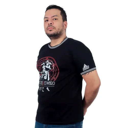 Un hombre con cabello corto y barba viste una camiseta gráfica negra con la imagen de Estilos Gamer y está de pie con confianza y las manos detrás de la espalda.