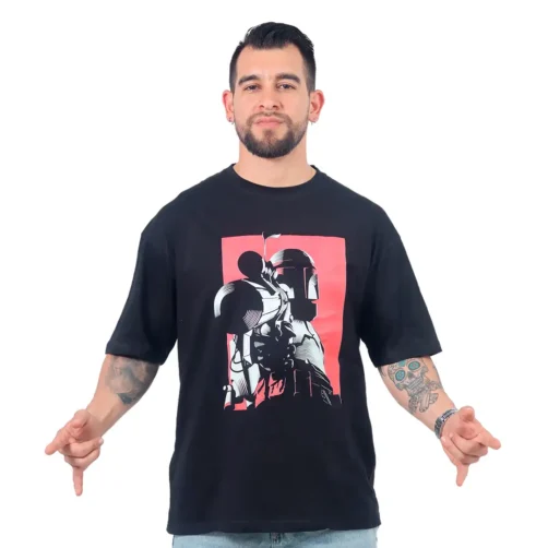 Un hombre vestido con el Cazador de Recompensas Star Wars - Camiseta Oversized, haciendo una pose con los dedos apuntando hacia abajo, encarna estilos de cultura pop al canalizar vibraciones icónicas mandalorianas a través de su atuendo.