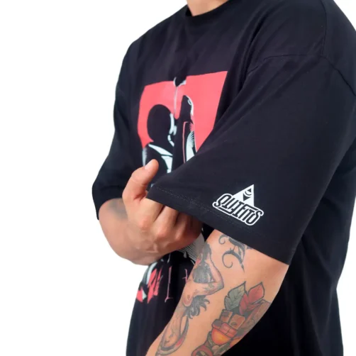 Una persona que viste una camiseta de gran tamaño que dice "Cazador de Recompensas Star Wars", resaltando su distintivo Estilos cultura pop, con tatuajes que adornan su brazo.