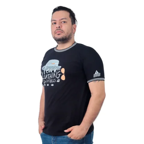 Un hombre que viste una camiseta de "Miedo y asco en Las Vegas - Camiseta Cuello Tejido" en color negro y con pantalones vaqueros azules está parado sobre un fondo blanco, ligeramente mirando hacia un lado.