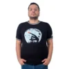 Una persona con un pendiente, vestida con un "Dedo E.T. - Camiseta Cuello Tejido" negro y pantalones vaqueros, se encuentra sobre un fondo blanco liso, canalizando sin esfuerzo los estilos retro.