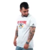 Una persona que viste una camiseta blanca "Ace Ventura Pet Detective", con gráficos vibrantes y detalles negros, transmite la onda pop de la cultura de Estilos.