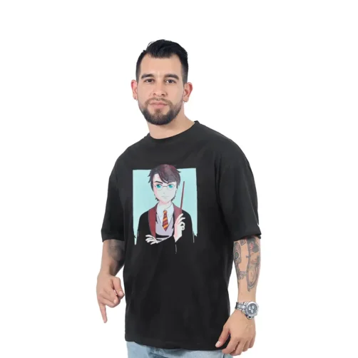 Un hombre con tatuajes lleva la camiseta de Harry Potter Anime - Camiseta Oversized, una camiseta negra que presenta un personaje de dibujos animados con gafas y una varita, que encarna estilos de cultura pop. Se para con confianza sobre un fondo blanco, lo que resalta su camiseta personalizada.