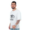 Una persona con barba que viste una "Fus Ro Dah de Skrim - Camiseta Oversized" con estilos de anime y pantalones de mezclilla está parada mirando ligeramente hacia un lado, gesticulando con su mano derecha.