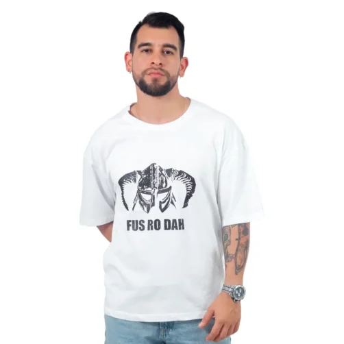 Un hombre barbudo luce la "Fus Ro Dah de Skrim - Camiseta Oversized", una camiseta blanca con un gráfico de casco y el icónico texto "FUS RO DAH", en honor a la cultura pop de Estilos.