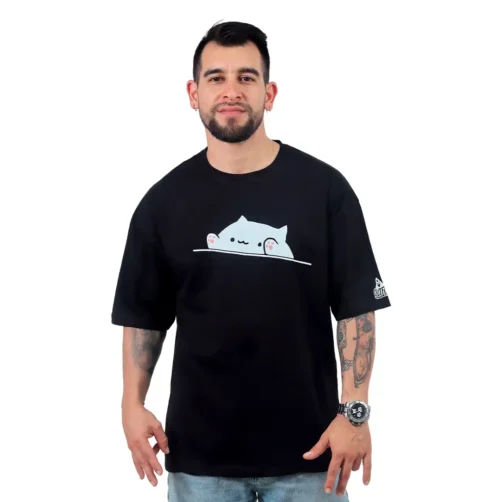 Un hombre con tatuajes viste la "Meme de Gatita - Camiseta Oversized", una camiseta negra adornada con un lindo gráfico de gato, que captura la esencia de los estilos culturales pop.