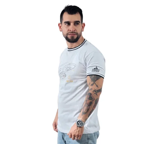 Un hombre con tatuajes, abrazando a Estilos Gamer, viste la USS Enterprise (NCC-1701) - Camiseta Cuello Tejido junto con unos jeans. Mira hacia un lado contra un fondo liso.