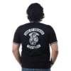 Se ve a una persona con cabello rizado desde atrás vistiendo una camiseta negra con el logo de Sons of Anarchy - Cuello Tejido, que combina hábilmente estilos retro con una declaración audaz.